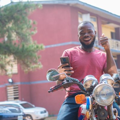 african bike man rejoices while checking his phone